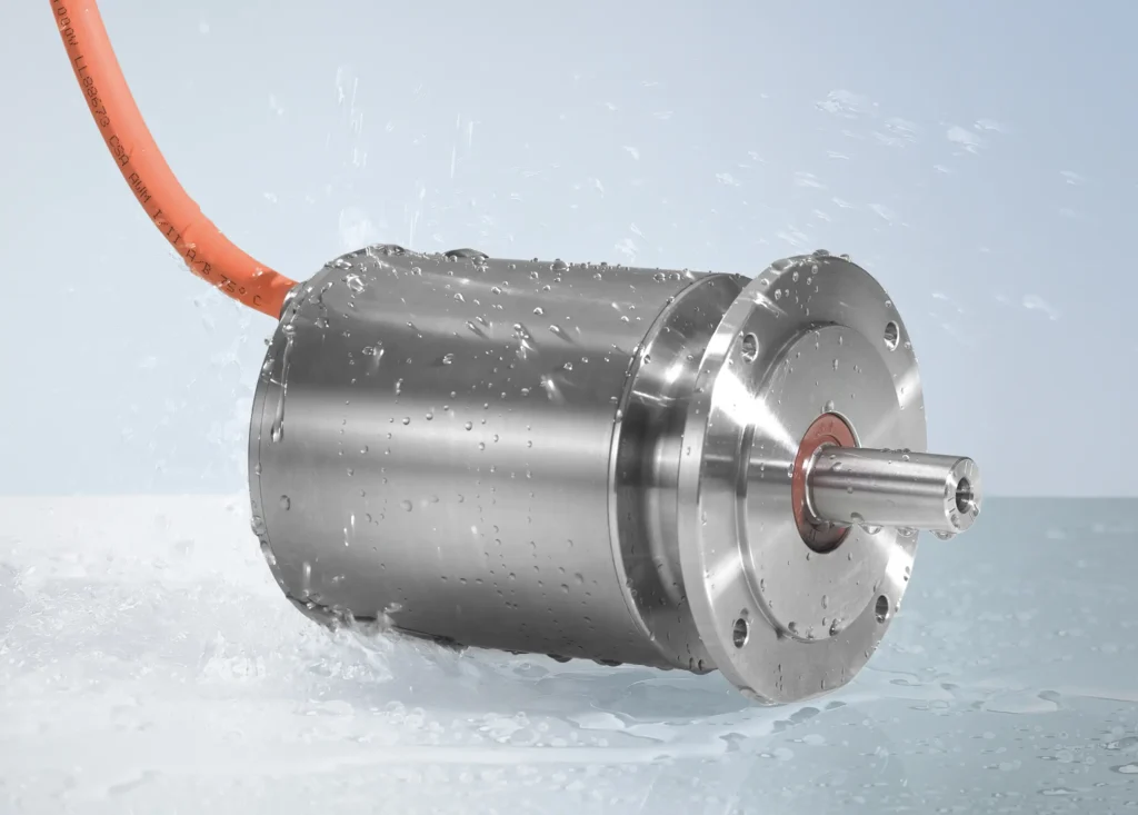 Servomotor de la serie AM8800 de Beckhoff en acero inoxidable con protección IP69K, mostrado durante una prueba de resistencia al chorro de agua a alta presión.